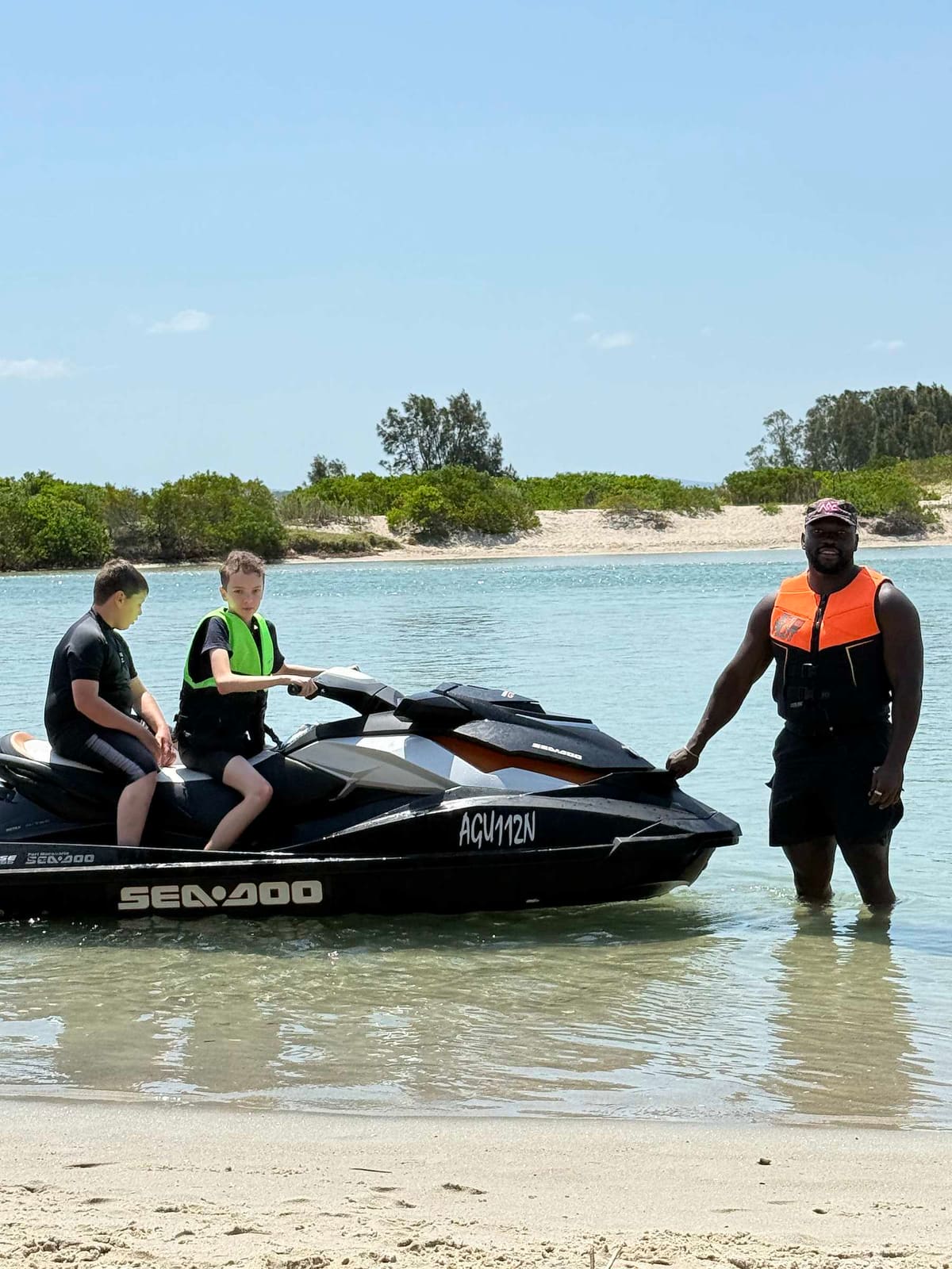 A Pal Supports worker steadying a jet ski in the shallows while two young people sit on it