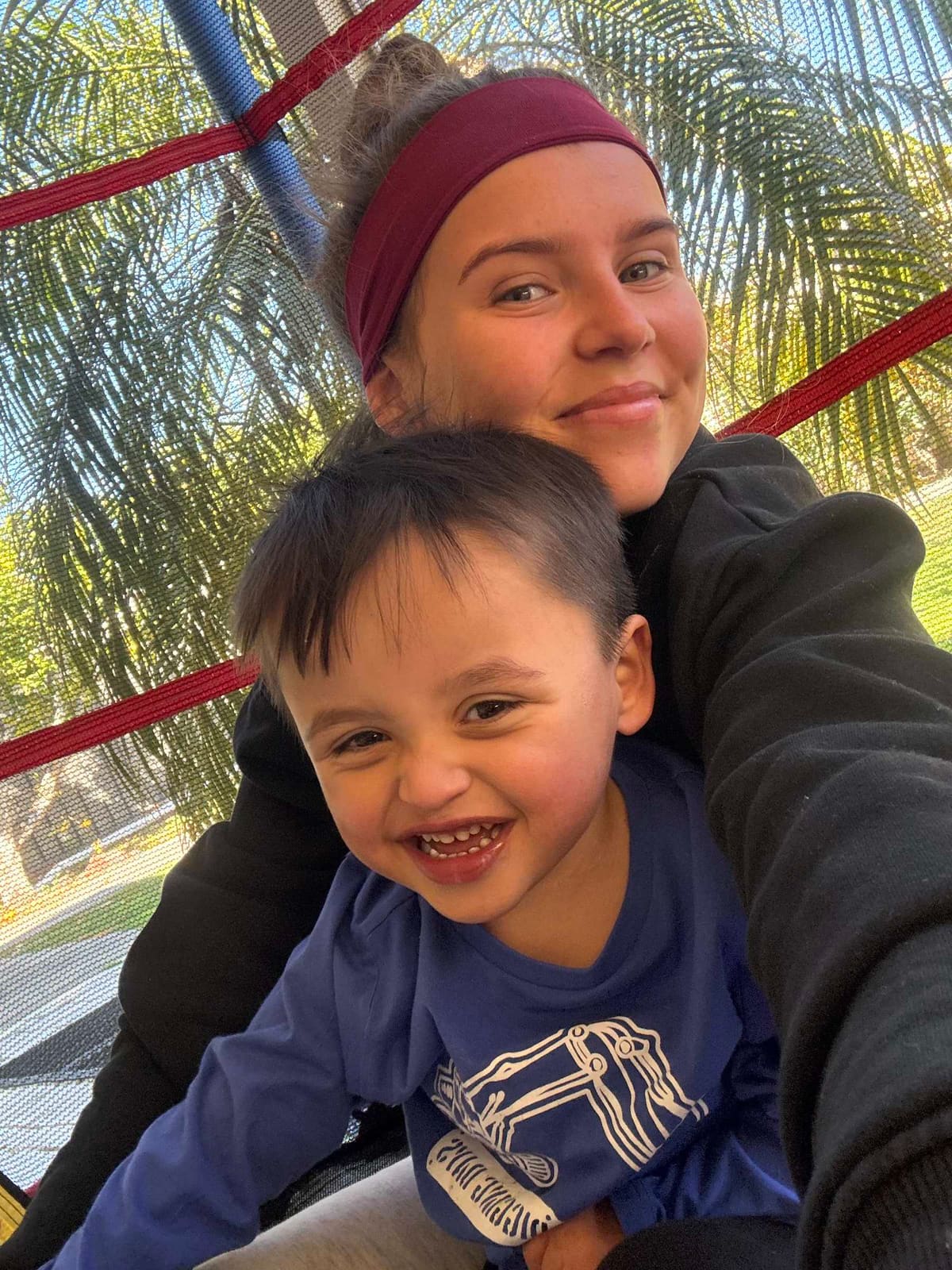 A Pal Supports worker and a small boy laughing together on a ride at a Hunter park