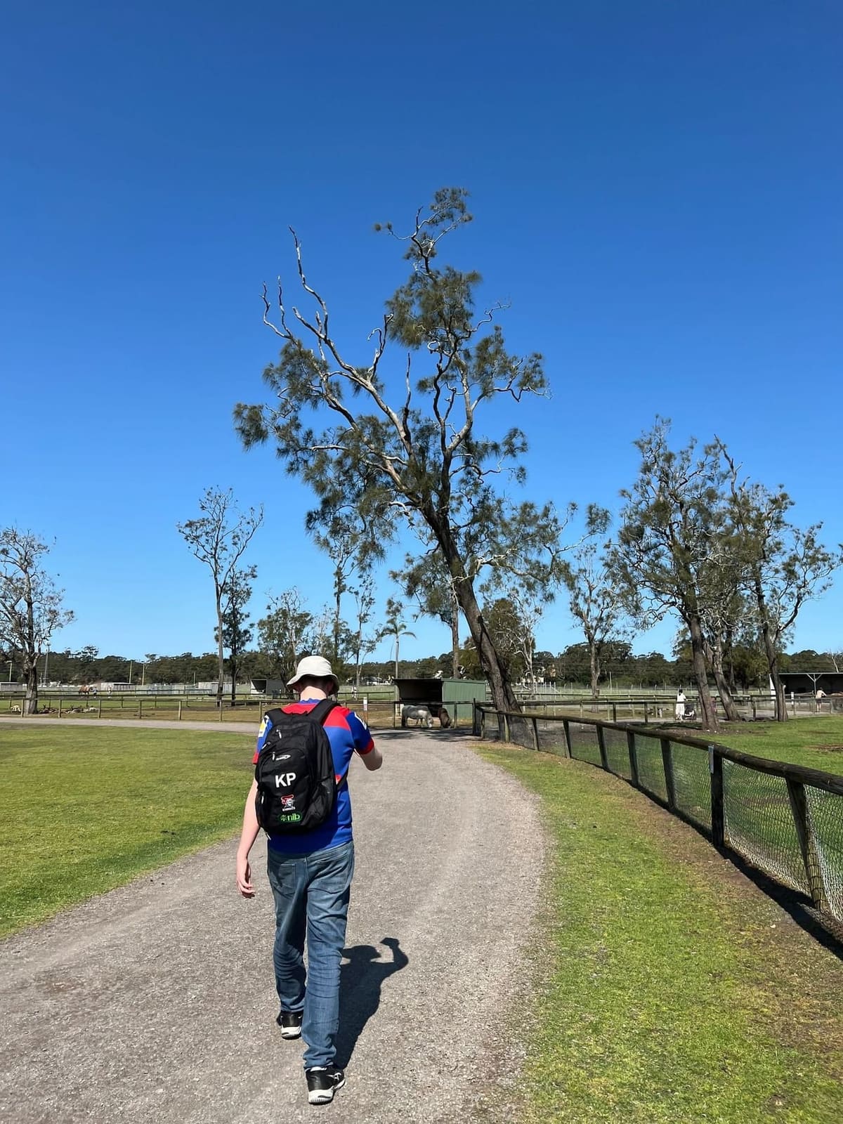 A teenager in a Newcastle Knights jersey walking a path at a Hunter animal park